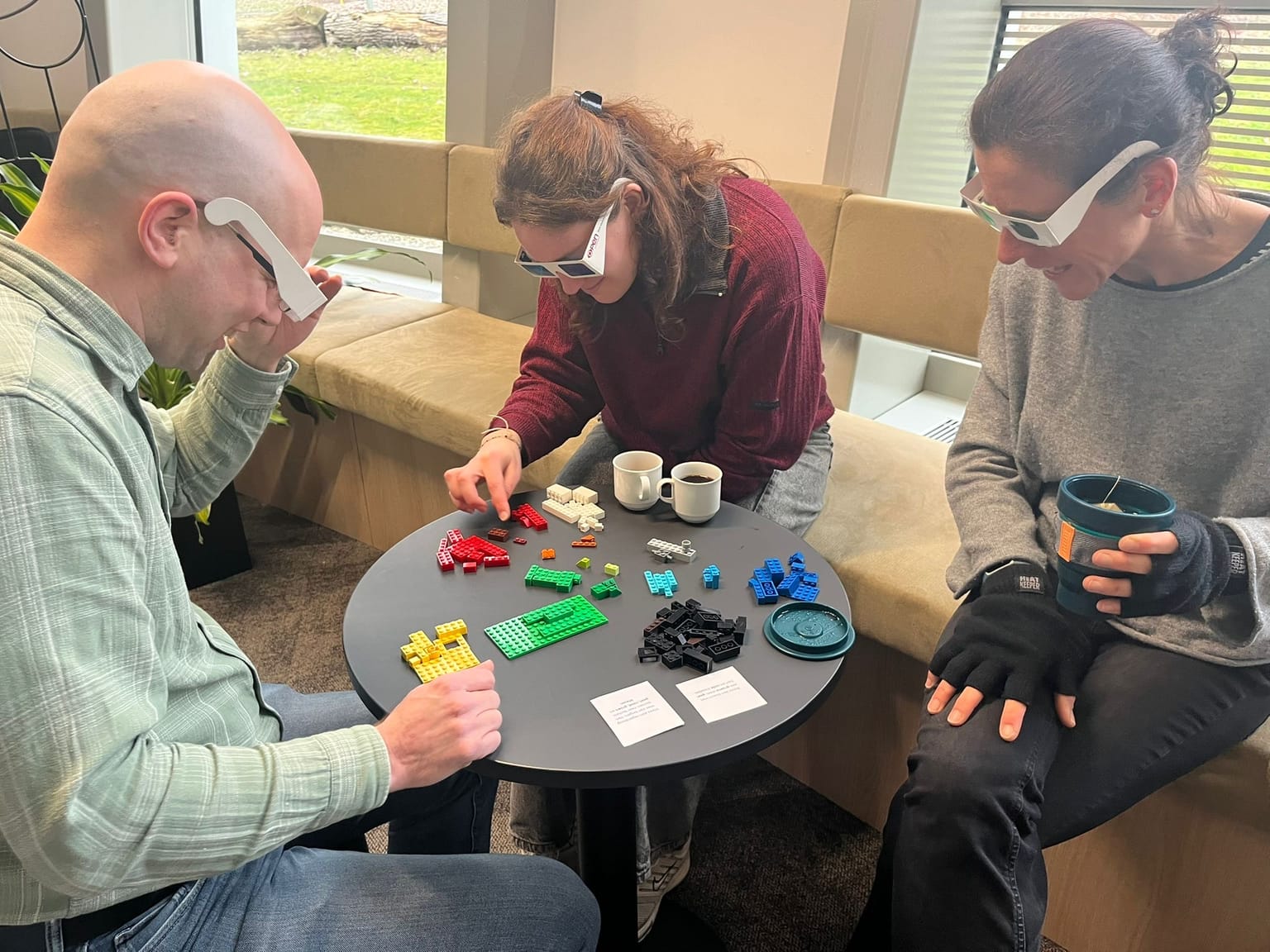 drie mensen zijn aan het kleurenblind LEGO bouwen